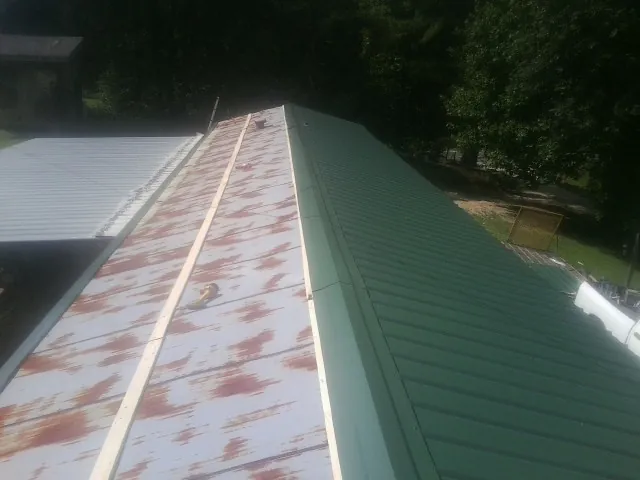 Old rusted panels beside newly installed green metal roofing — Wind Damage Roof Repair by Roofing Brothers in South Fork