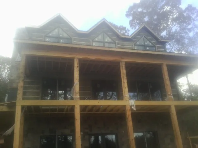 Dormers and porch framing on a large log home under construction — Roof Coating work by our crew in South Fork