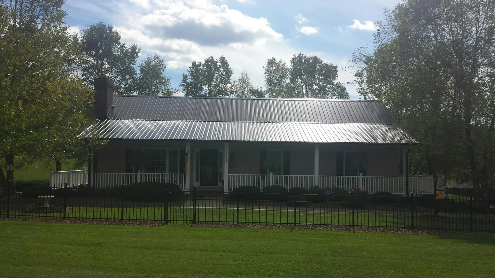 Gray metal roof on a brick ranch with a full width front porch — Gutter Guard Installation work by our crew in South Fork