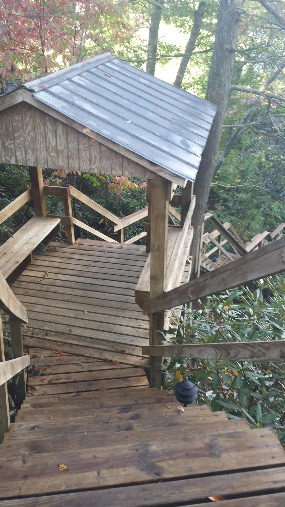 Metal roofed shelter over wooden steps on a wooded walkway — Skylight Repair & Installation work by our crew in South Fork
