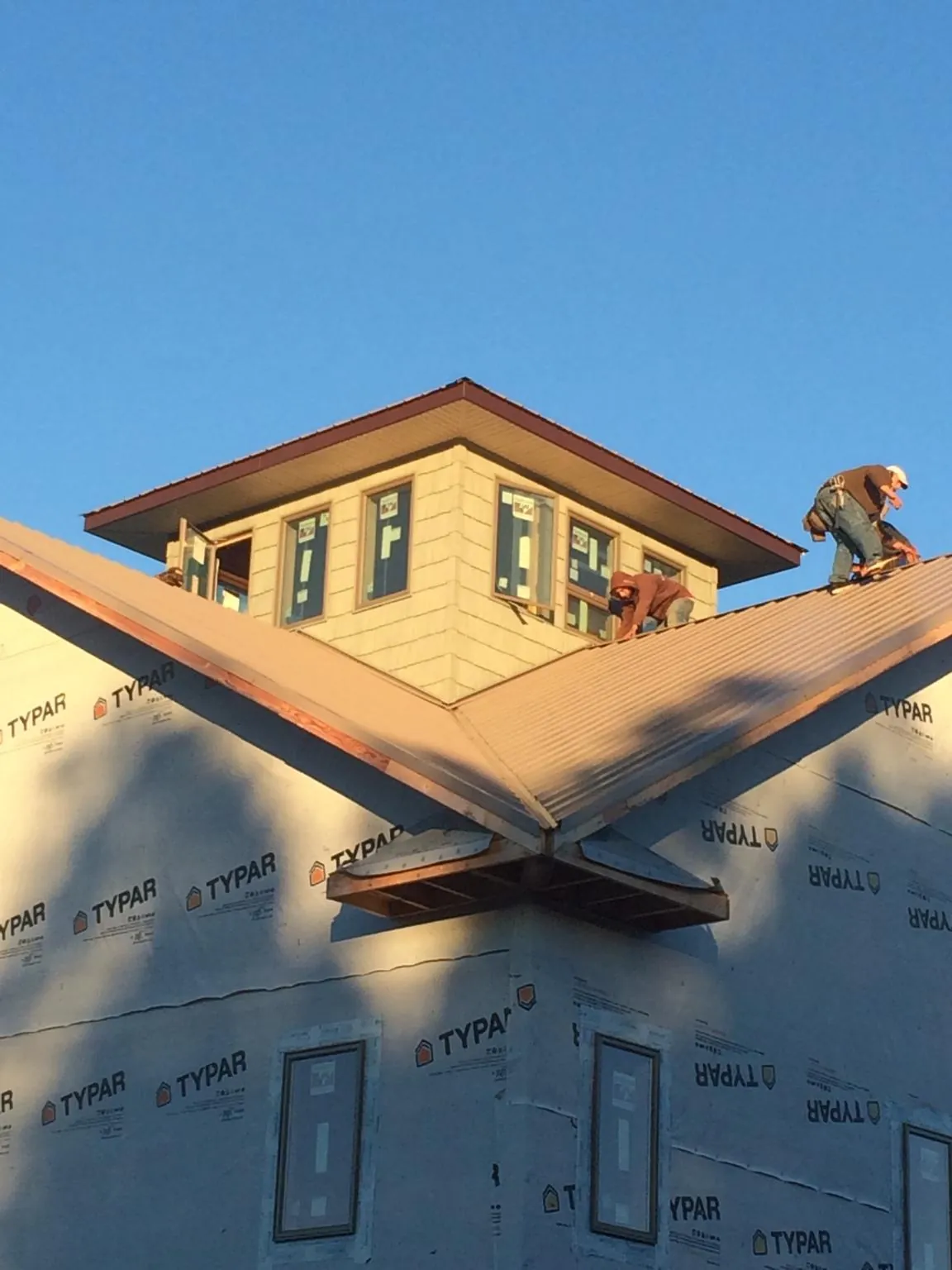Roofers working around a rooftop cupola on a new metal roof at sunset — Roof Waterproofing in South Fork by Roofing Brothers